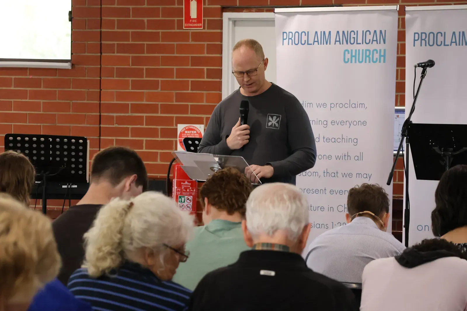 A Bible reading at Clyde Public Hall in front of the Proclaim Anglican Church banners